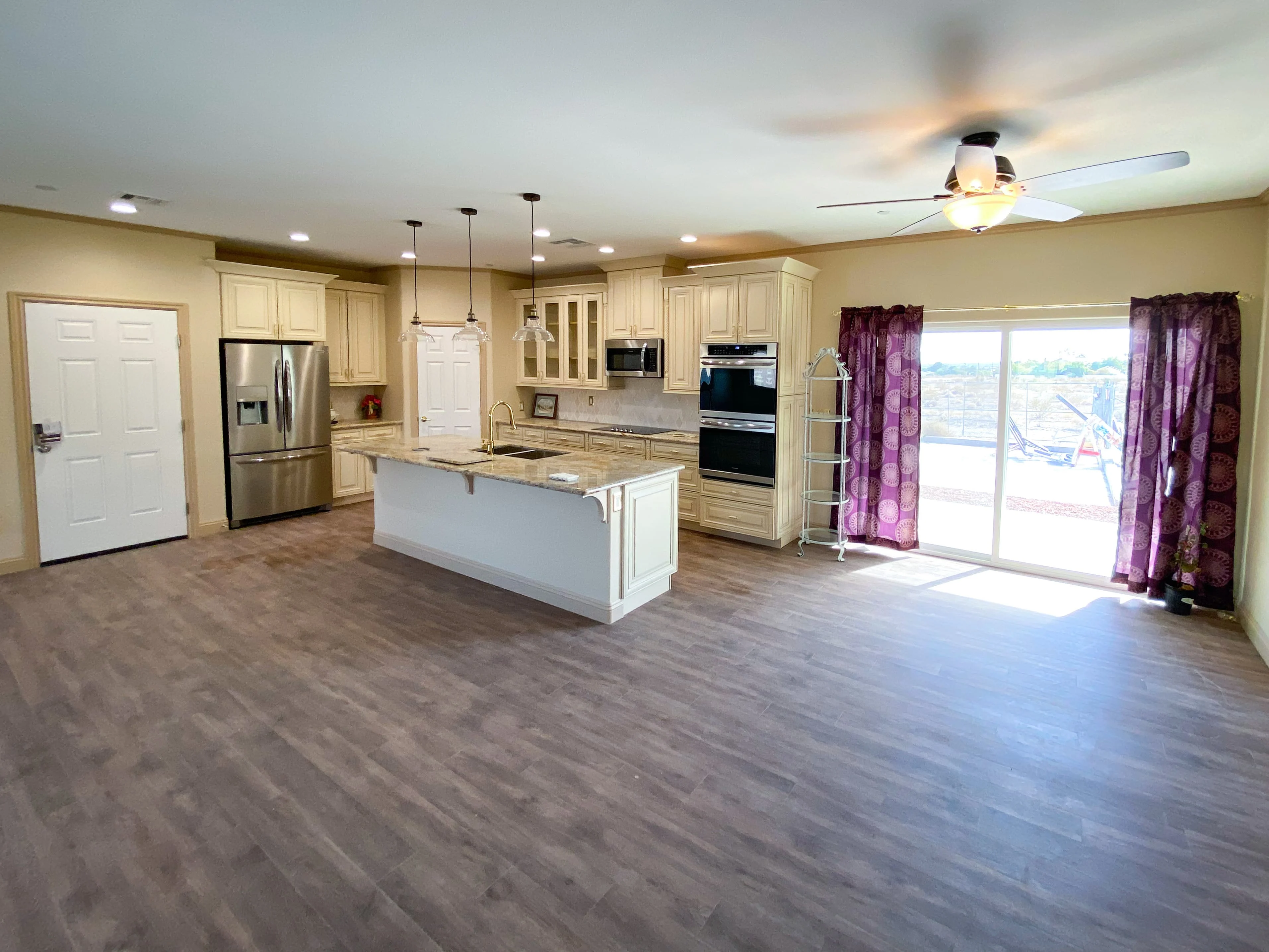 Modern stove and microwave set against warm granite countertops with cream-colored custom cabinets - Custom Home built by James Development Corp. Las Vegas, NV.