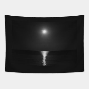 A grayscale shot of a boat in the calm sea with the reflection of the moon at night Tapestry