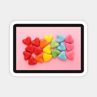 Heart-shaped multi-colored candy ordered in rainbow colors and shape on a pink background Magnet