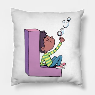 boy blows soap bubbles while sitting on the letter L Pillow