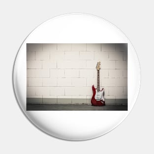 Red electric guitar against white brick wall Pin