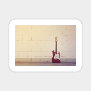 Red electric guitar against white brick wall Magnet