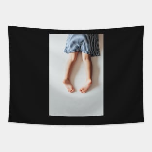 Legs of Small Girl Lying on White Tabletop Tapestry