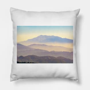 Mountain layers rising to distant peak through hazy light and different color bands. Pillow