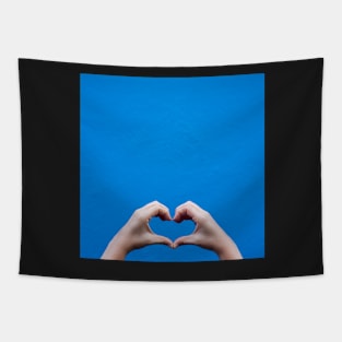 Love sign made by hands against a blue wall Tapestry