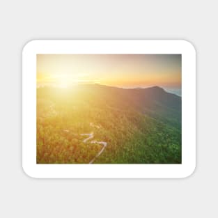 Aerial view of curvy mountain road through a jungle ay sunset Magnet