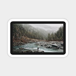 A man standing on jagged rocks in a fast-flowing river in the wilderness Magnet