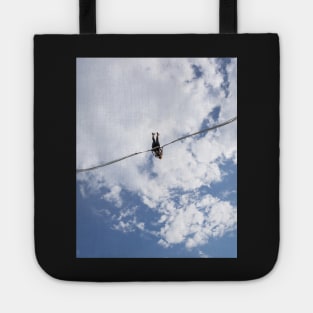 Girl in slingshot against blue cloudy sky Tote