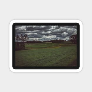 Dark moody sky over meadow and forest Magnet