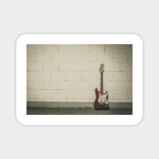 Red electric guitar against white brick wall Magnet