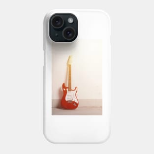 Red electric guitar standing left against white raw wall Phone Case