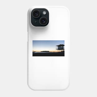 Silhouetted against golden glow of sunrise lifesafers lookout on Mount Maunganui beach New Zealand. Phone Case