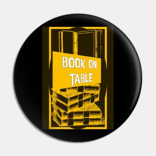 Book of table yellow and black designed totes, phone cases, mugs, masks, hoodies, notebooks, stickers pins, Pin