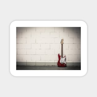 Red electric guitar against white brick wall Magnet