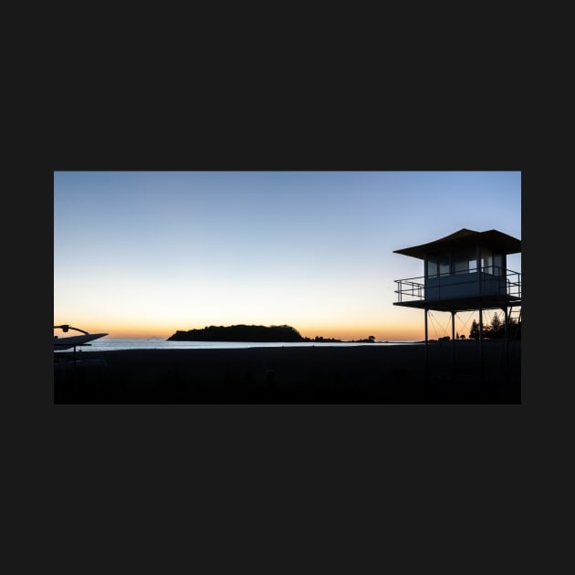 Silhouetted against golden glow of sunrise lifesafers lookout on Mount Maunganui beach New Zealand. by brians101