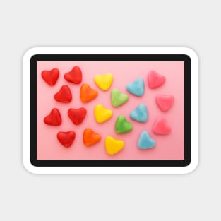 Heart-shaped colorful candy arranged in rainbow colors, on a pink background Magnet