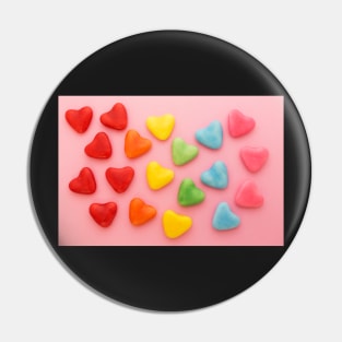 Heart-shaped colorful candy arranged in rainbow colors, on a pink background Pin