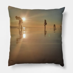 Silhouetted people in a row on a sand beach. Pillow