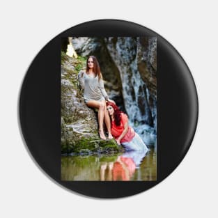 Two beautiful young women leaning on rocks beside a river Pin