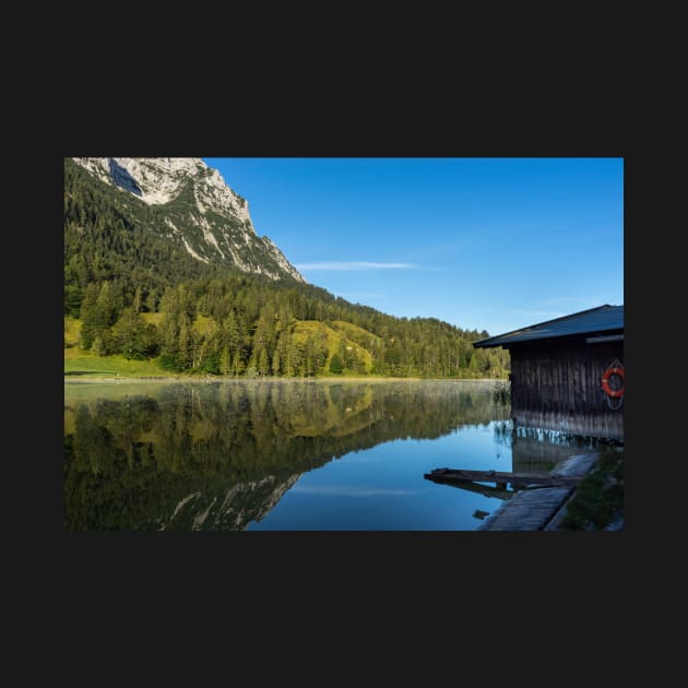 Lake water reflections with wooden boathouse wide angle. Amazing shot of a wooden house in the Ferchensee lake in Bavaria, Germany, in front of a mountain belonging to the Alps. by EviRadauscher