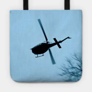 A Bell UH-1 Huey Iroquois flying low over trees Tote