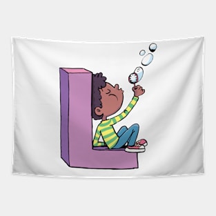 boy blows soap bubbles while sitting on the letter L Tapestry