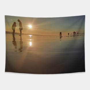 Silhouetted people in a row on a sand beach. Tapestry