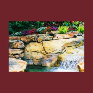 Camiseta con flores de colores sobre rocas junto a un arroyo