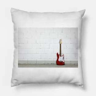 Red electric guitar against white brick wall Pillow