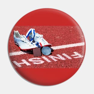 Racing spikes with medals at the finish line Pin