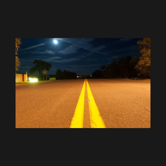 Yellow road lines stretch ahead in night light by brians101