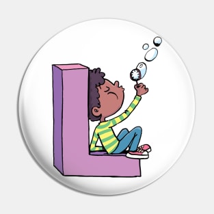 boy blows soap bubbles while sitting on the letter L Pin