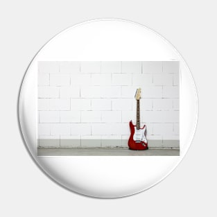 Red electric guitar against white brick wall Pin