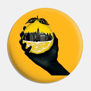 A hand holding a city inside a lemon Pin