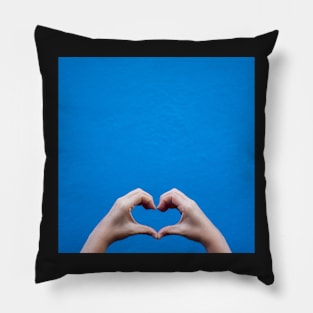 Love sign made by hands against a blue wall Pillow