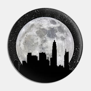 Silhouette of a city against a giant moon Pin