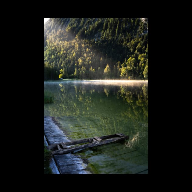 Ray of sunlight on misty lake. Wooden pier in front. Amazing shot of the Ferchensee lake in Bavaria, Germany. Scenic foggy morning scenery at sunrise. by EviRadauscher