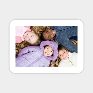 Smiling children lying on autumn leaves (F001/1826) Magnet