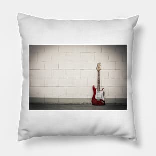 Red electric guitar against white brick wall Pillow