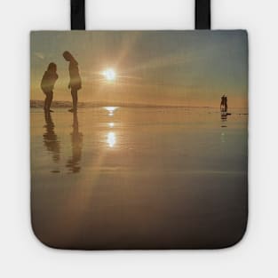 Silhouetted people in a row on a sand beach. Tote