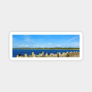 People fishing with a line on an old stone pier on a clear day Magnet