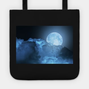 Blue super moon glowing against cloudy sky Tote