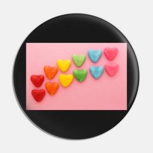 Heart-shaped Candy arranged in rainbow order on a pink background Pin