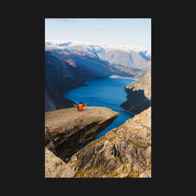 Man sitting on Trolltunga rock meditating by mooonthemoon