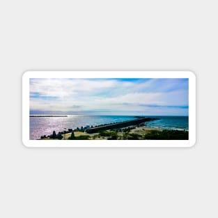 Pier with concrete breakwaters. Seascape, glare on the water of the Baltic Sea, rays of light Magnet