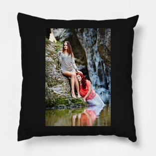 Two beautiful young women leaning on rocks beside a river Pillow