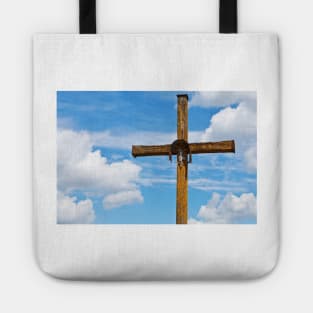 Figurine of Jesus Christ on a wooden cross against under blue cloudy sky Tote