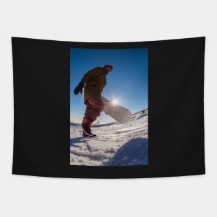 Snowboarder walking against blue sky Tapestry