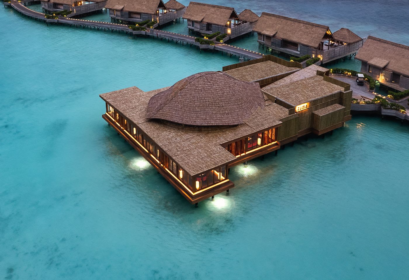 Zuma, the overwater restaurant at the Waldorf Astoria Maldives Ithaafushi, lit up at dusk