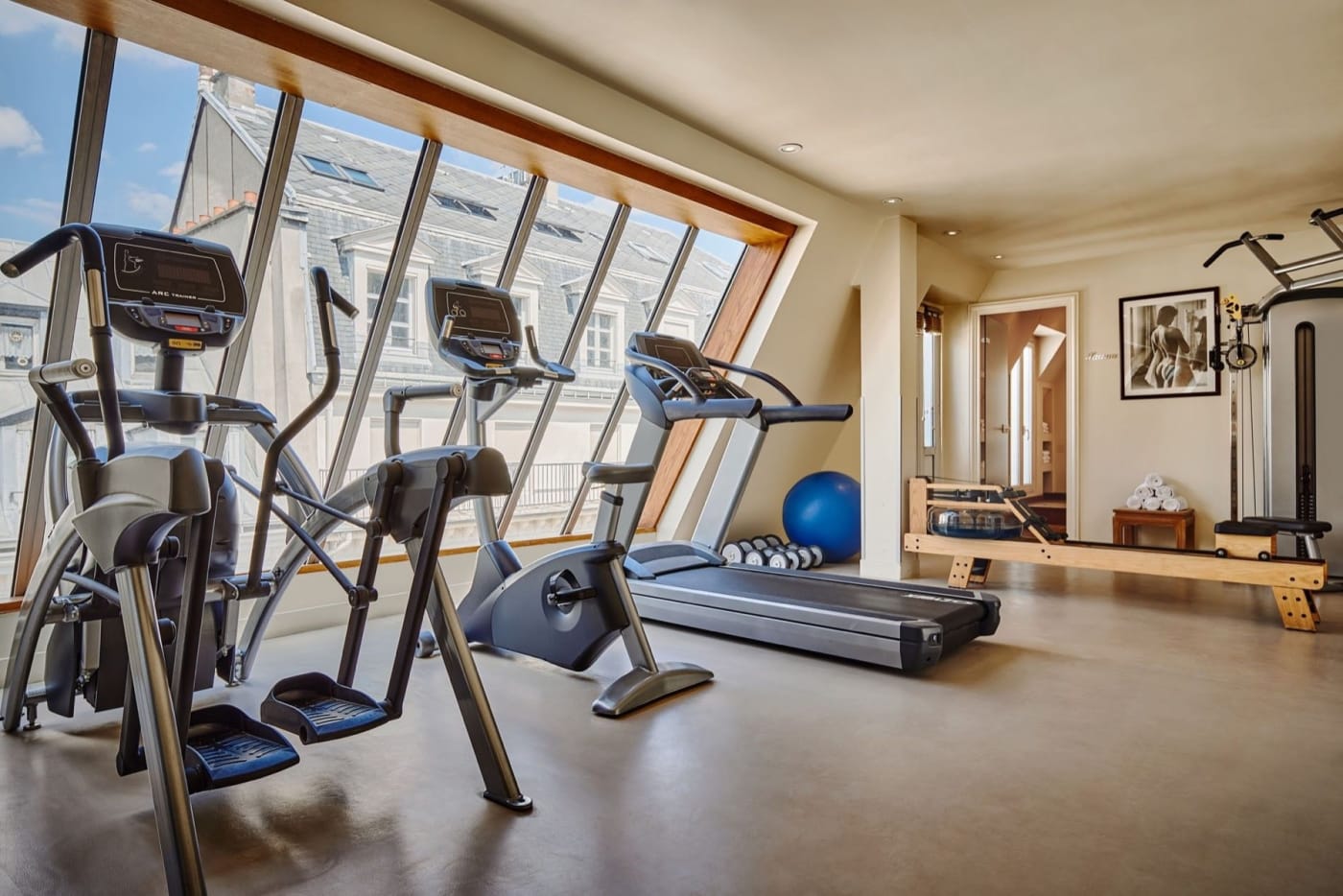 Salle de sport sous les toits de l'hôtel Westminster à Paris, baies vitrées sur les immeubles voisins